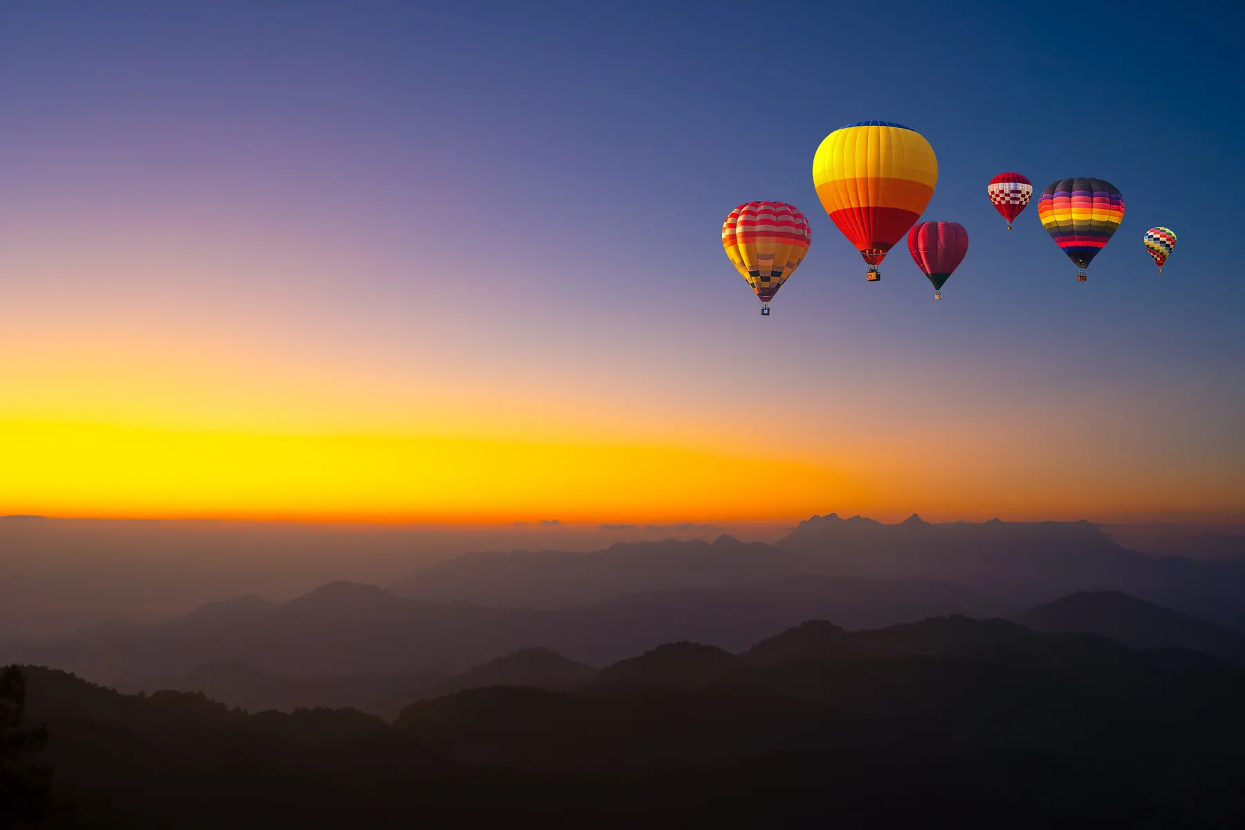 Hot air balloons rising over a sunrise ridge