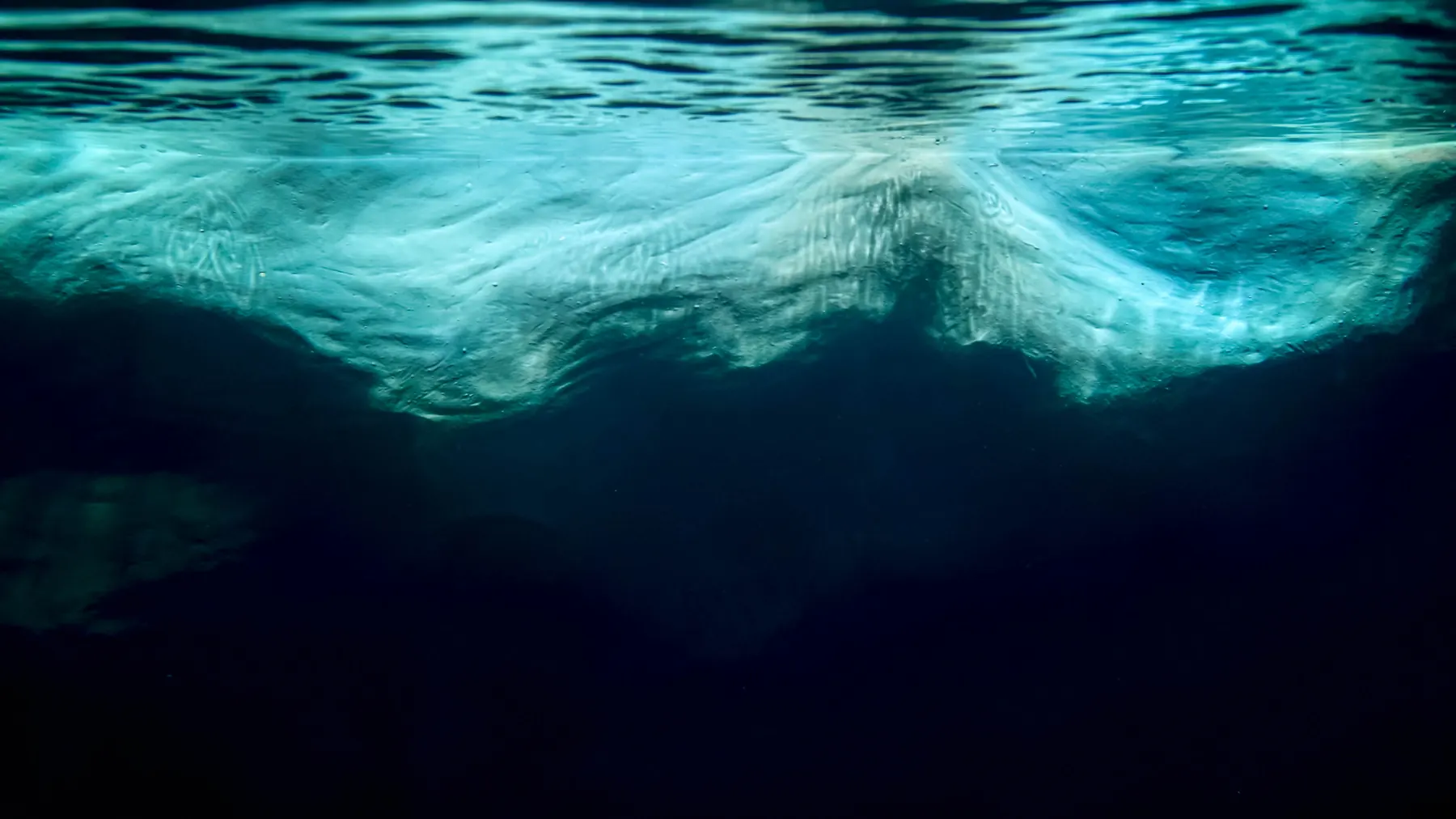 An iceberg seen from underwater, most of it hidden beneath the surface