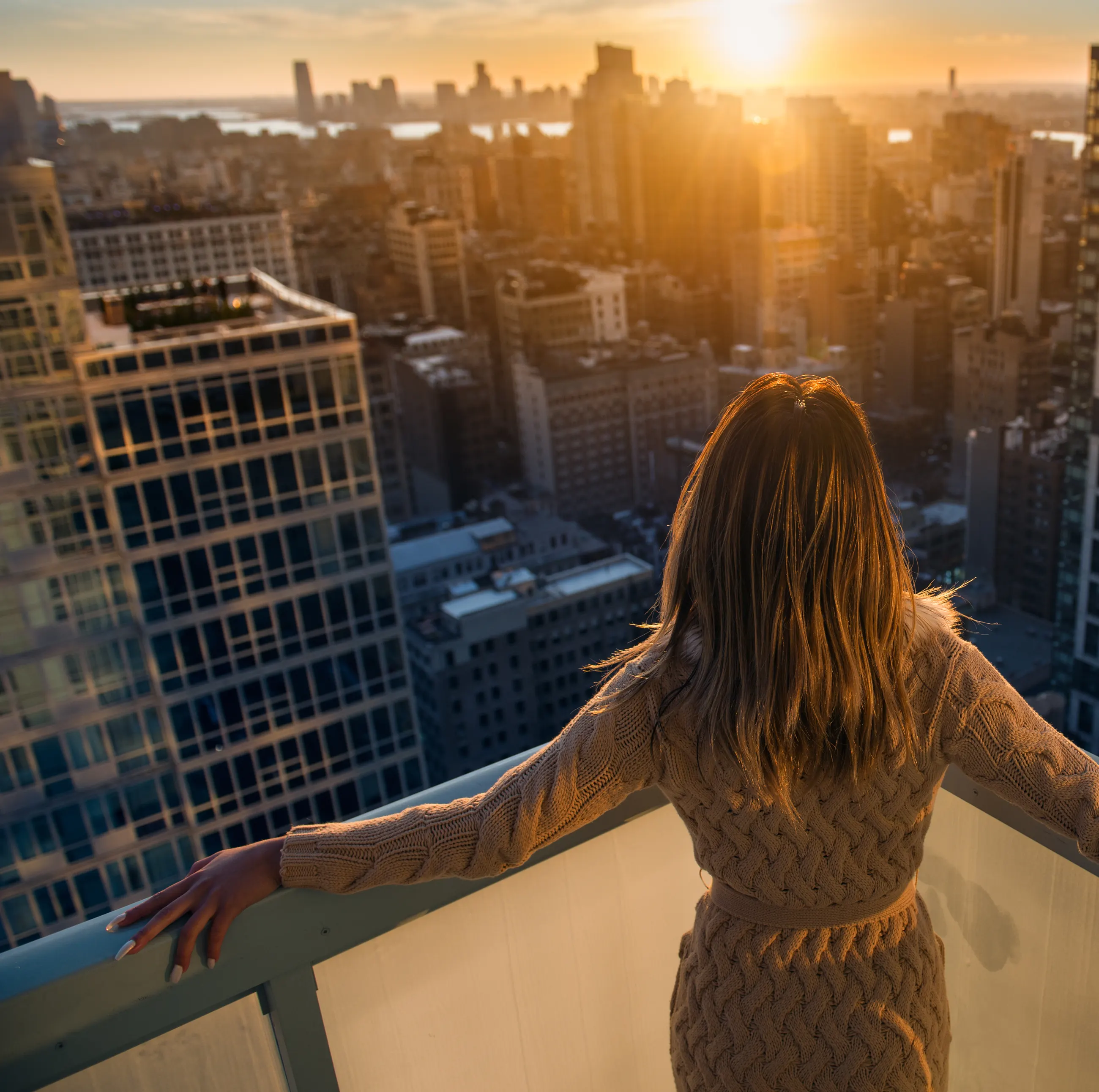 A business owner on a balcony overlooking the city at sunrise