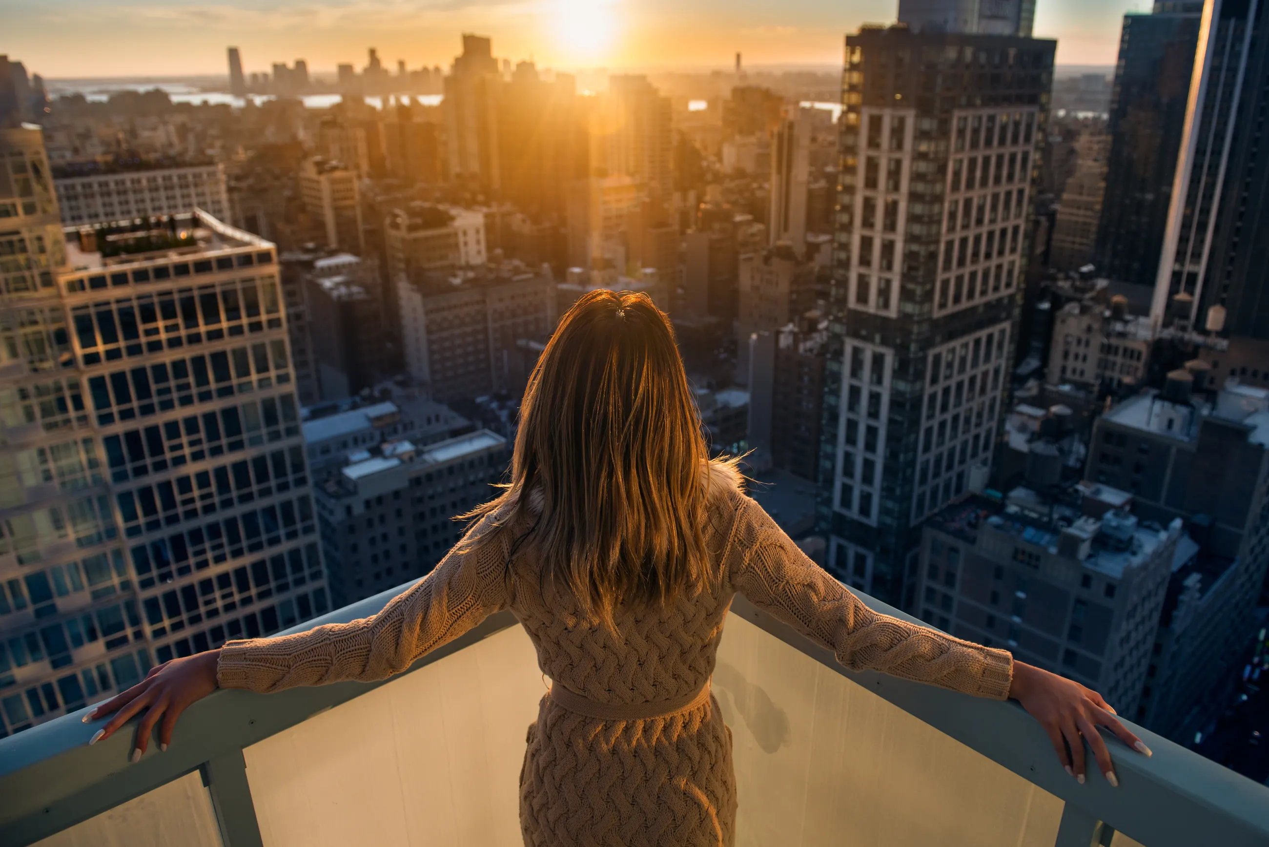 A business owner on a balcony overlooking the city at sunrise
