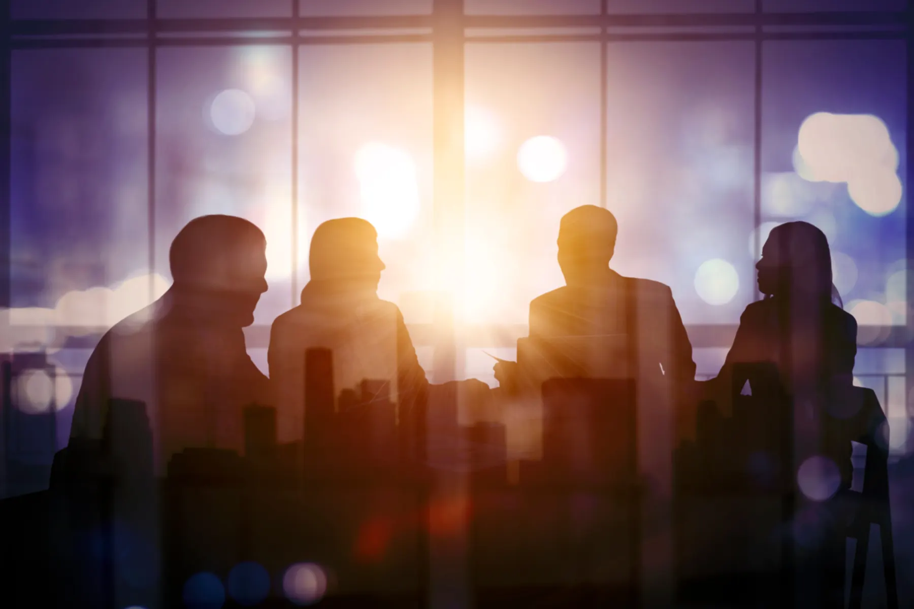 A team meeting silhouetted against warm window light